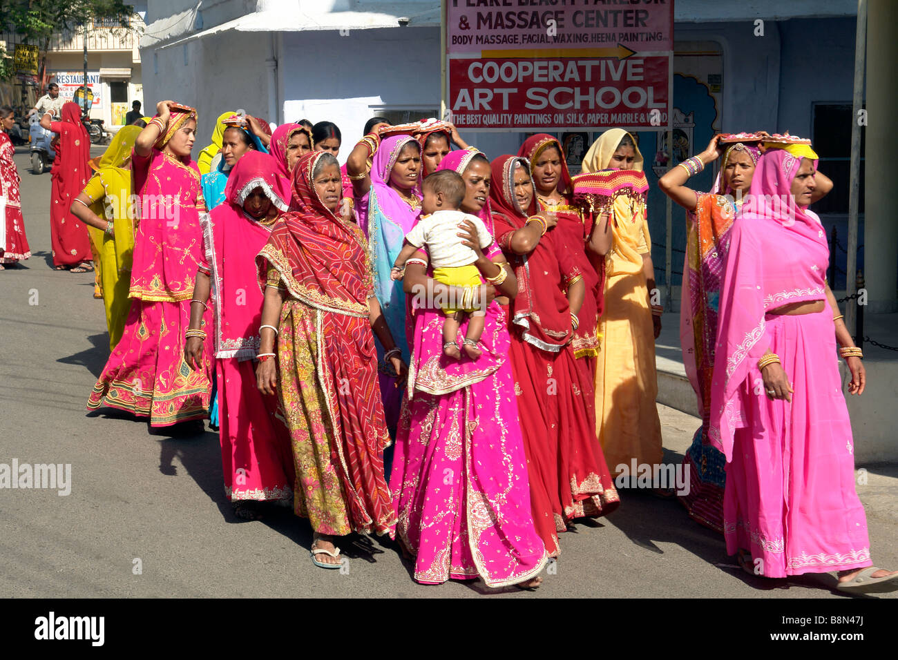 Le donne indiane in abito tradizionale a piedi attraverso i vicoli di udaipur durante una cerimonia puja Foto Stock