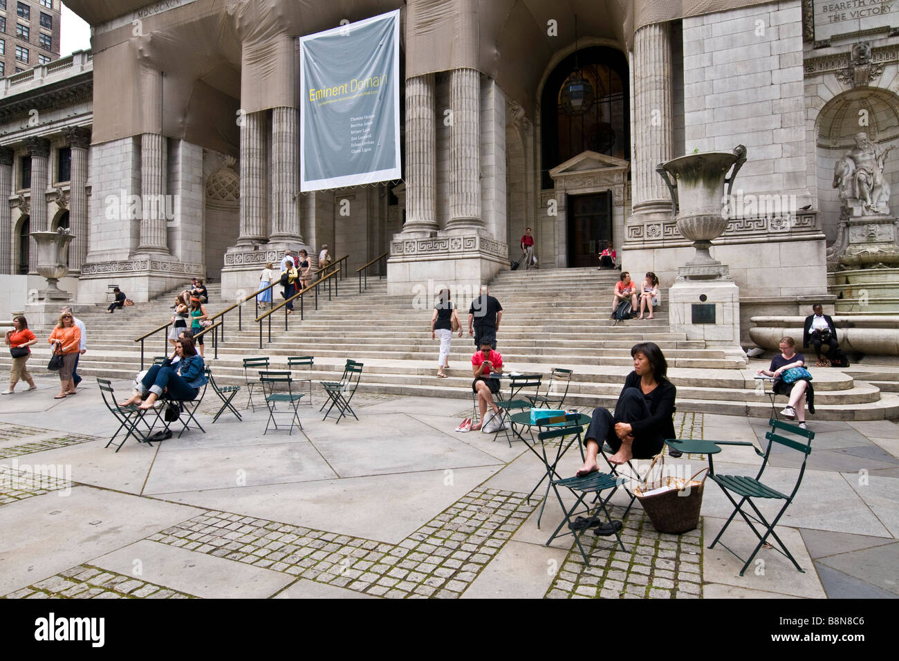 Persone sedute sui gradini e sulle sedie al di fuori della biblioteca pubblica di New York Foto Stock
