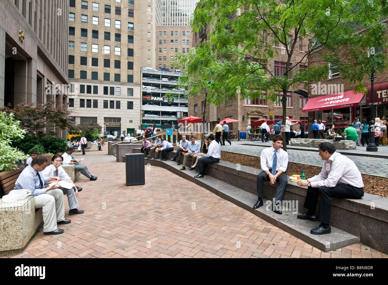 Scena di strada con diversi downtown office i lavoratori al di fuori seduta avente il loro pranzo Foto Stock