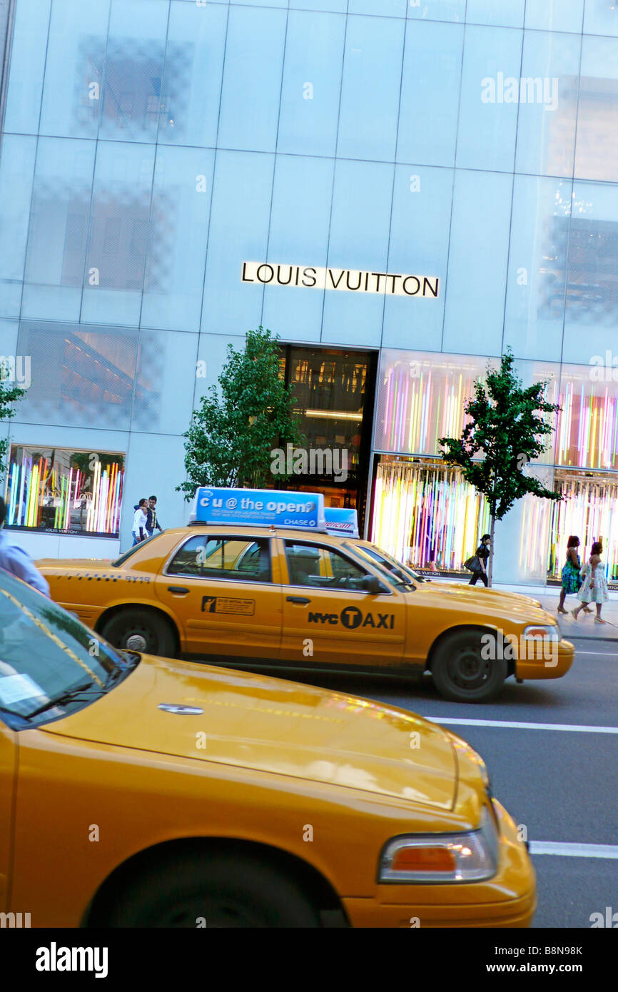 Giallo taxi passando per il negozio Louis Vuitton sulla quinta avenue Foto Stock