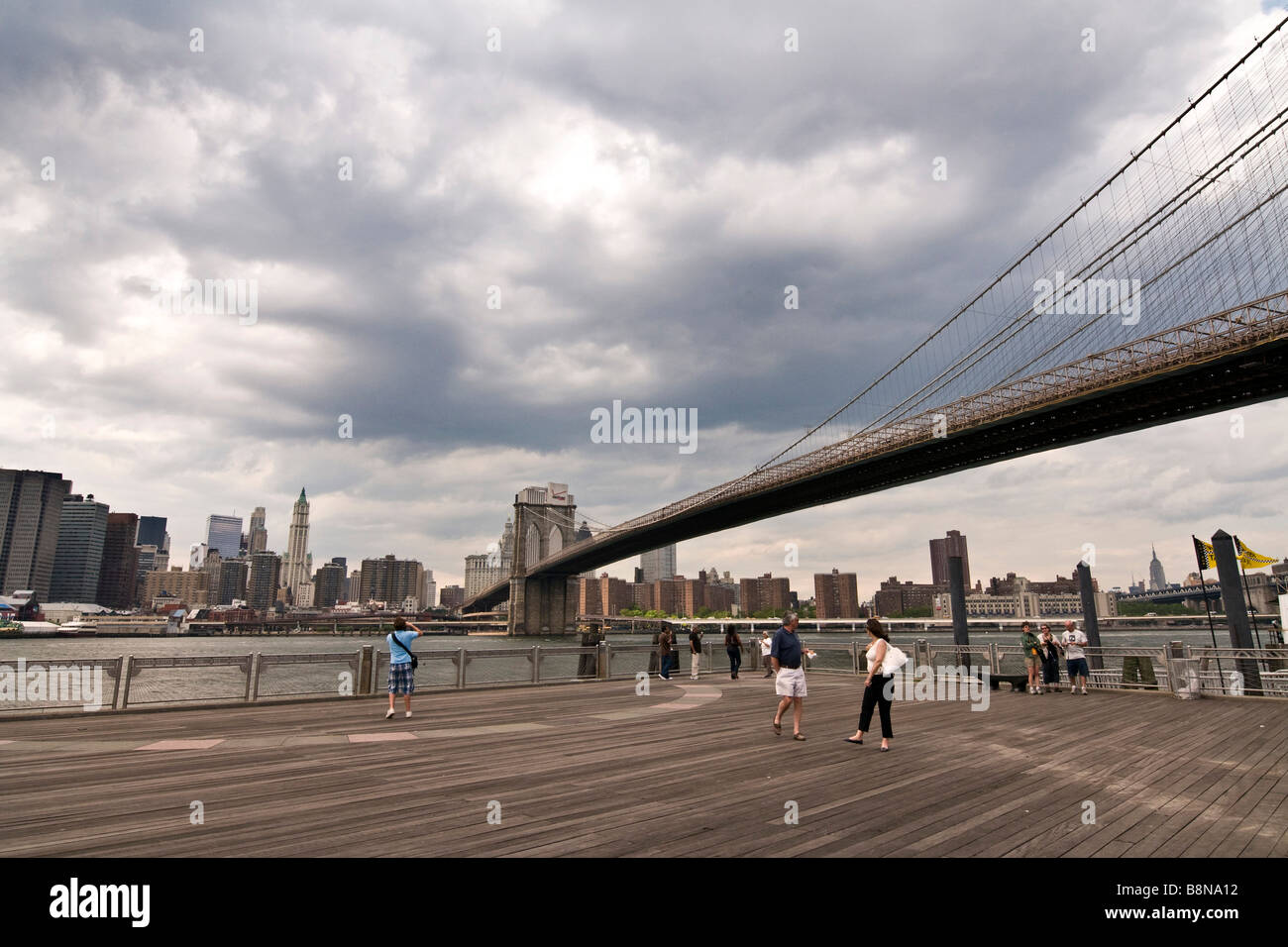 Pedoni e turisti la visualizzazione di ponte di Brooklyn contro lo sfondo dello skyline di Manhattan Foto Stock