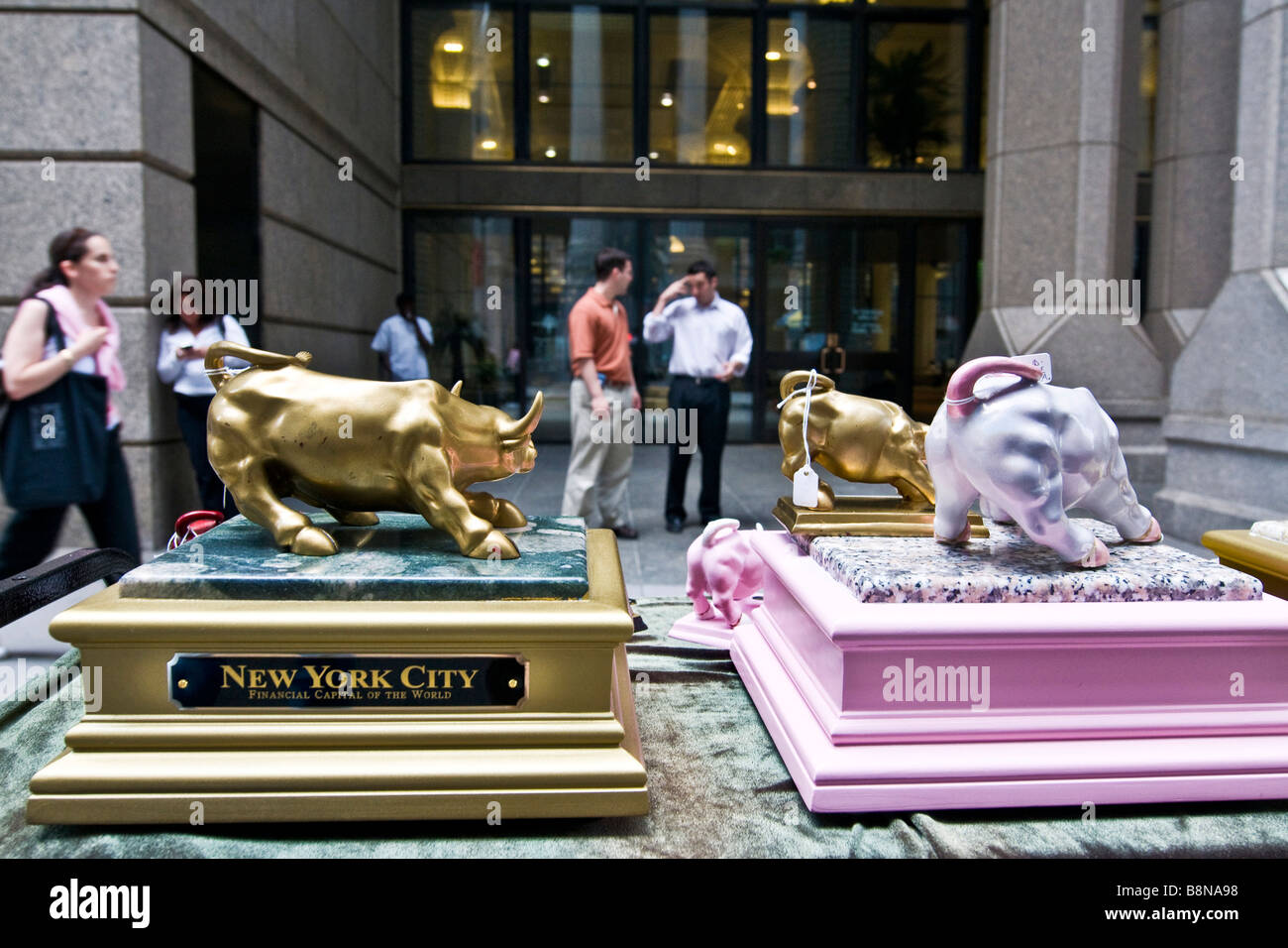 Pedoni passando le statue di tori in Manhattan Foto Stock