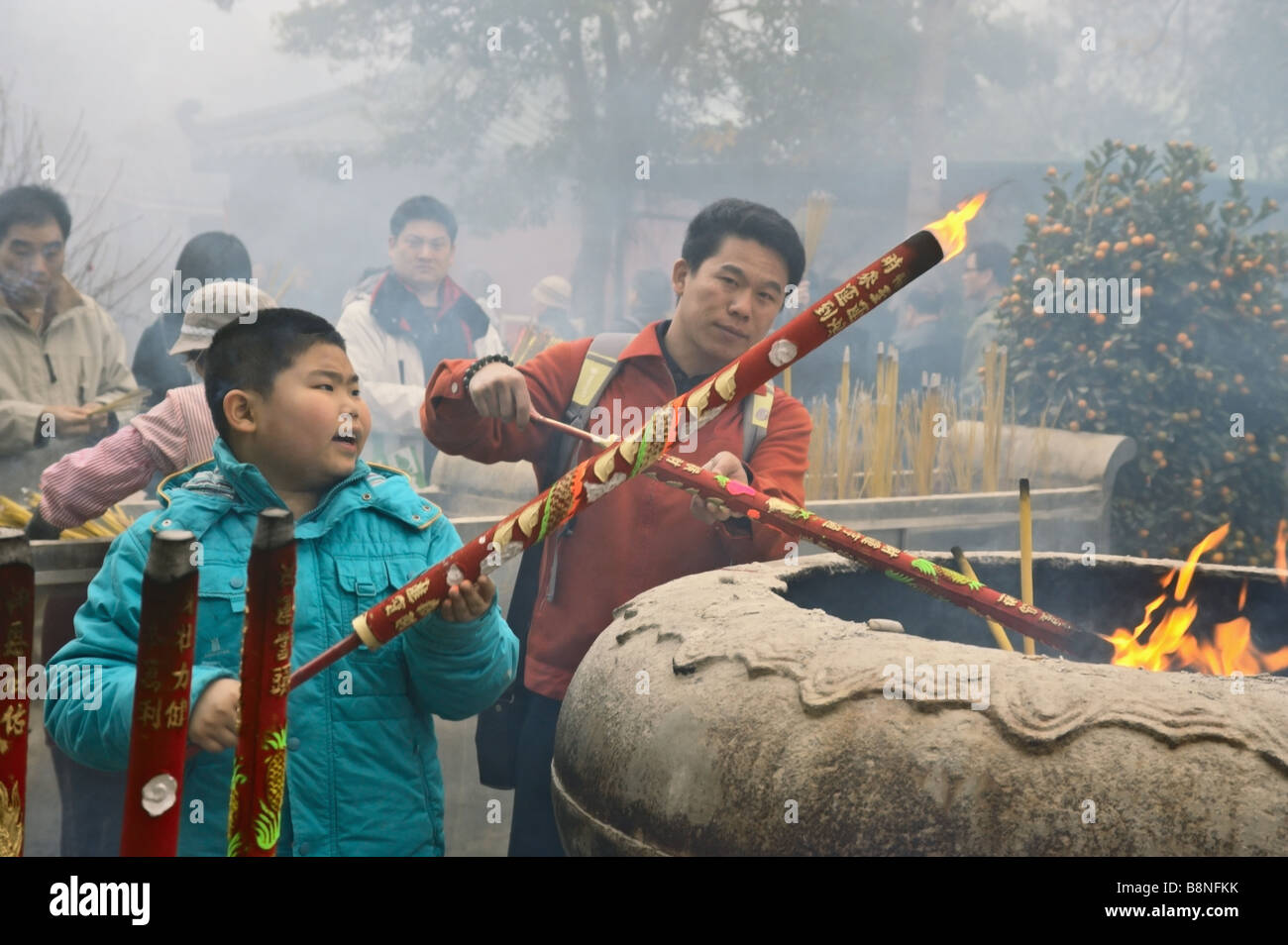 Uomo e per ragazzo grande luce bastoncini di incenso al Monastero Po Lin su foggy primo giorno del nuovo anno lunare 2009 Lantau Hong Kong Foto Stock