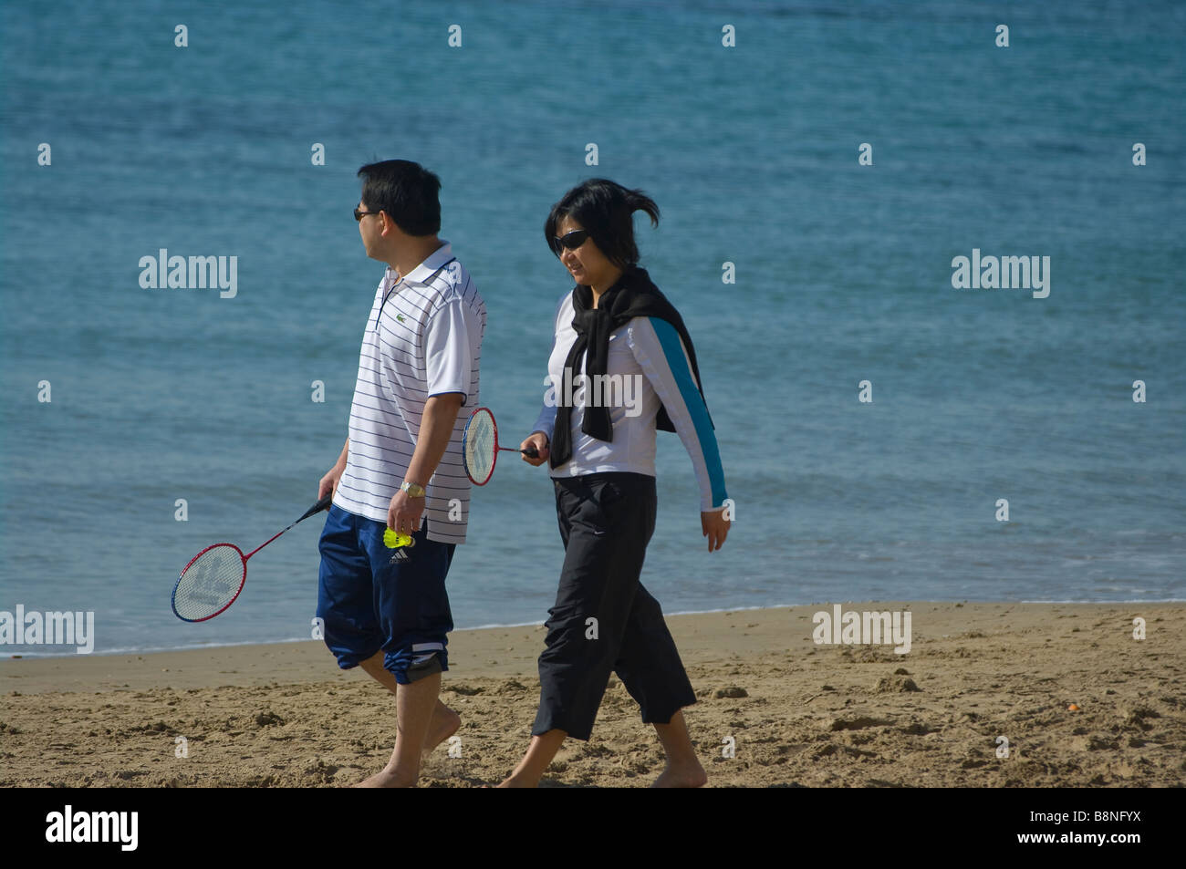 Oriental coppia giovane camminando lungo la spiaggia spiaggia Foto Stock