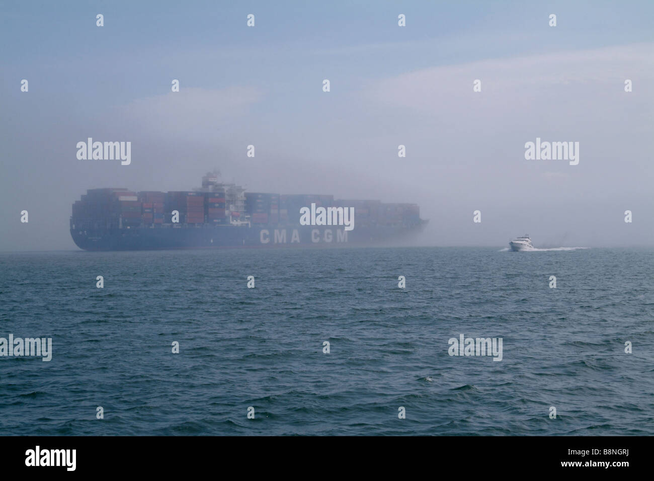 Contenitore nave scomparendo in un banco di nebbia di mare Foto Stock