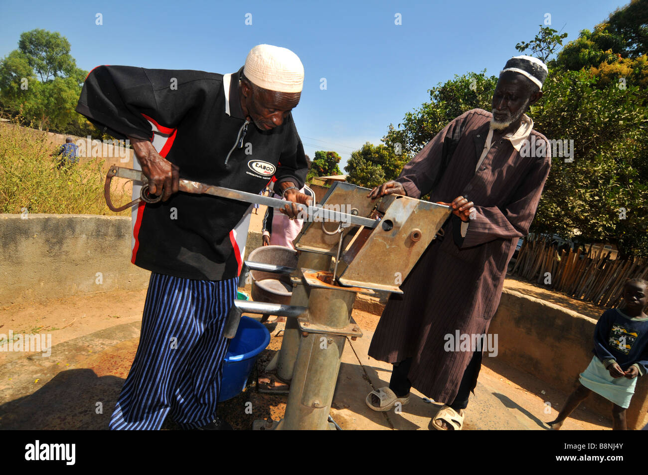 Gli uomini riparare una pompa ad acqua in un villaggio in Gambia, Africa occidentale Foto Stock