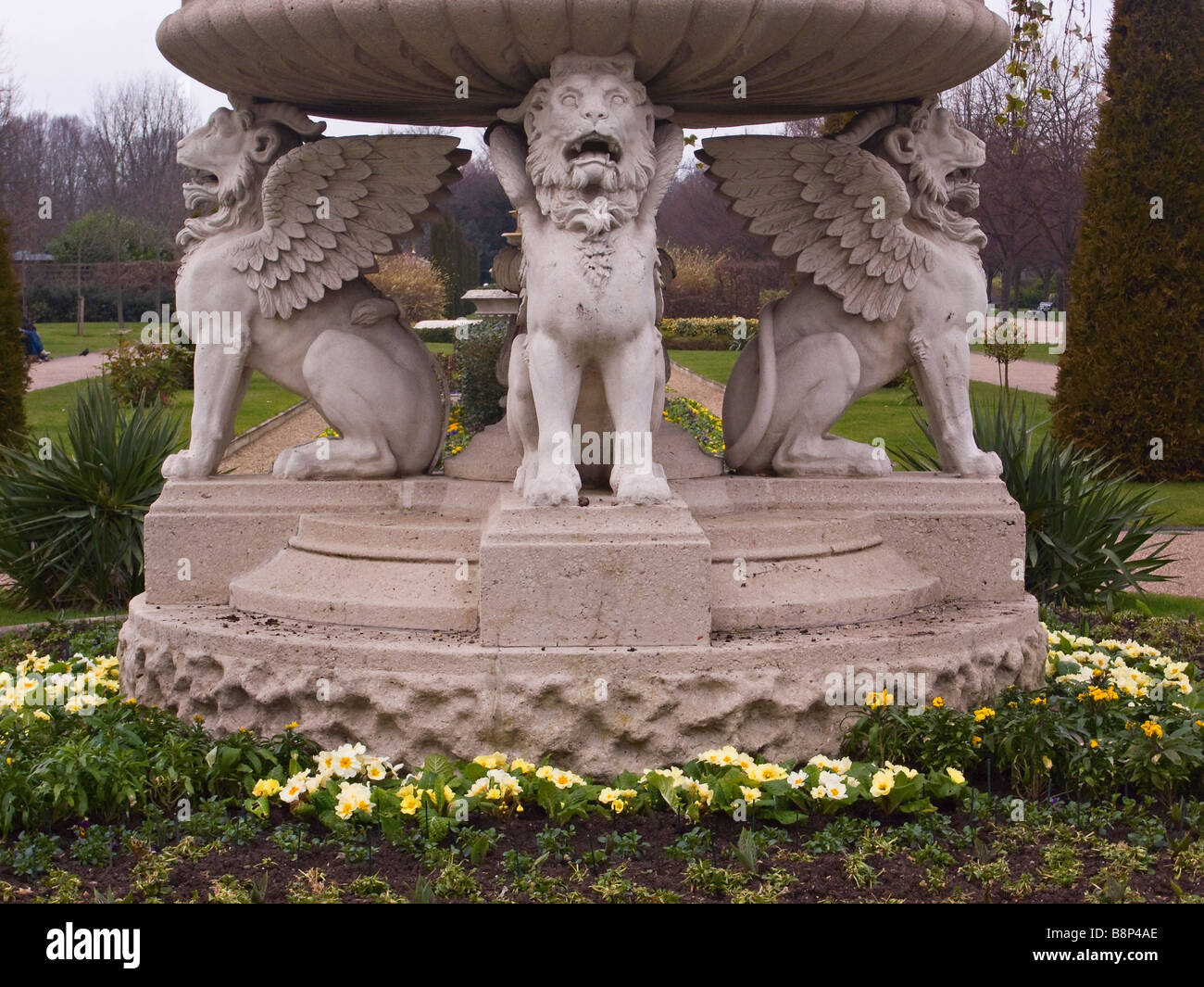 La fontana della ciotola in pietra Griffin Tazza o Lion Vase circondata Da Primule nella primavera di inizio a Regents Park, Londra, Regno Unito Foto Stock