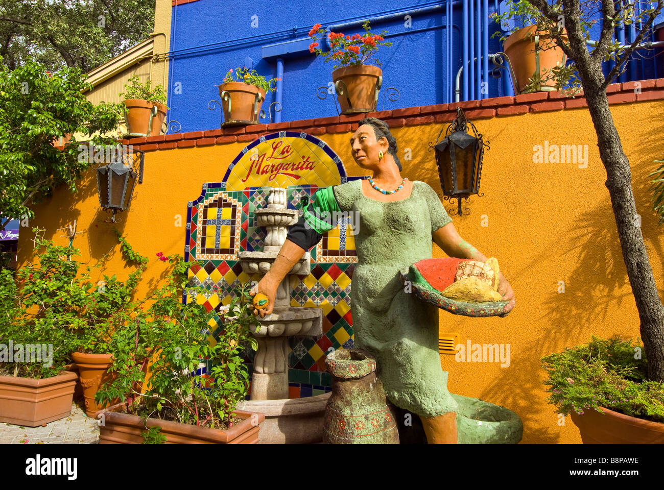 La Piazza del Mercato di San Antonio TX con colorati statua di una donna messicana accanto a fontana e luminosa parete gialla Foto Stock