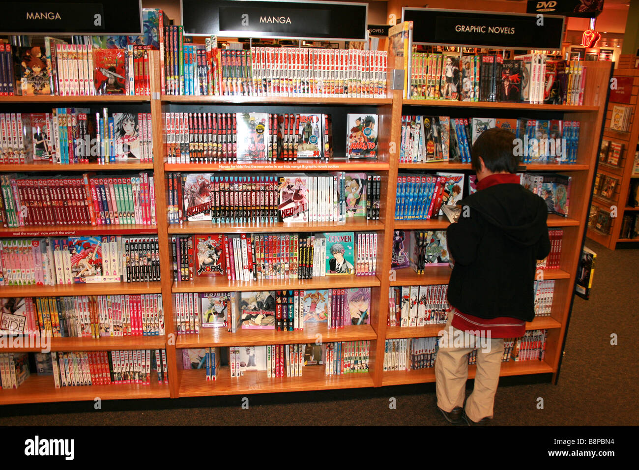 Bambino di nove anni la navigazione selezione di manga anime fumetti giapponesi in bookstore Foto Stock