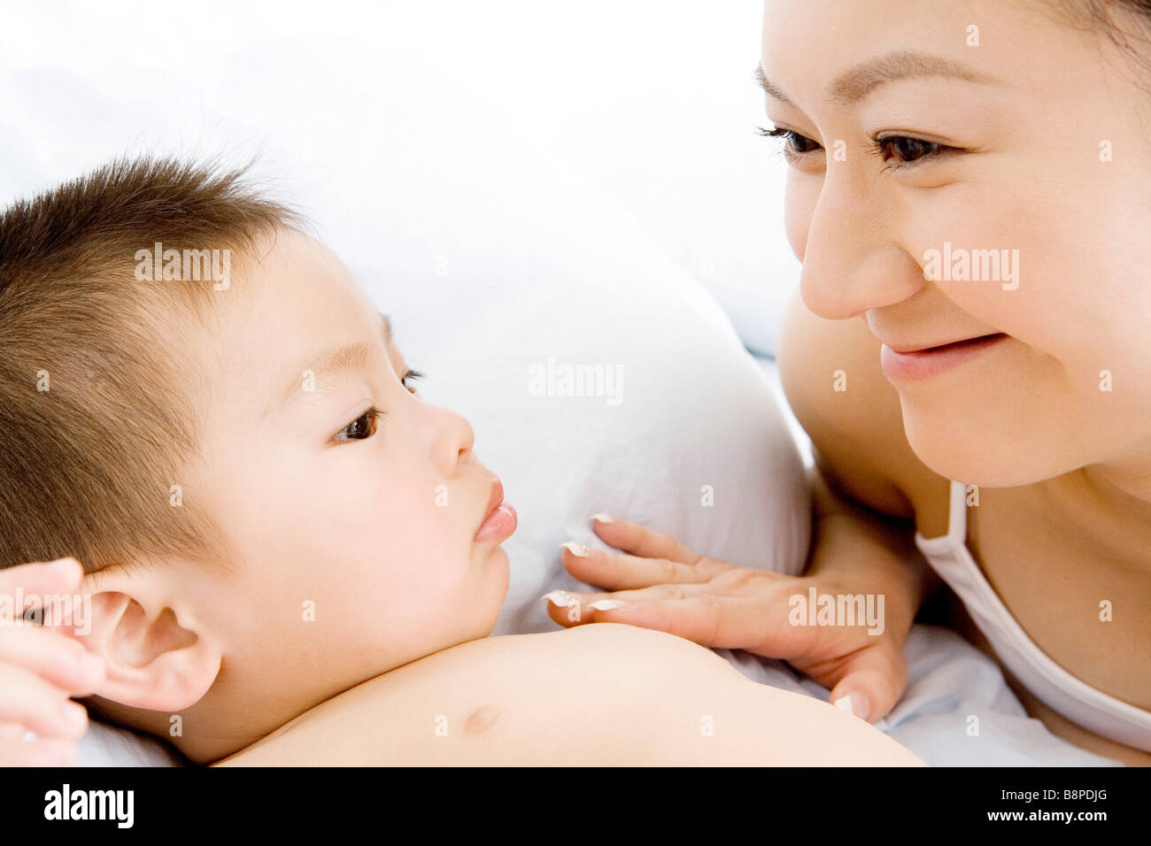Baby boy e madre sul letto ritratto sorridente Foto Stock