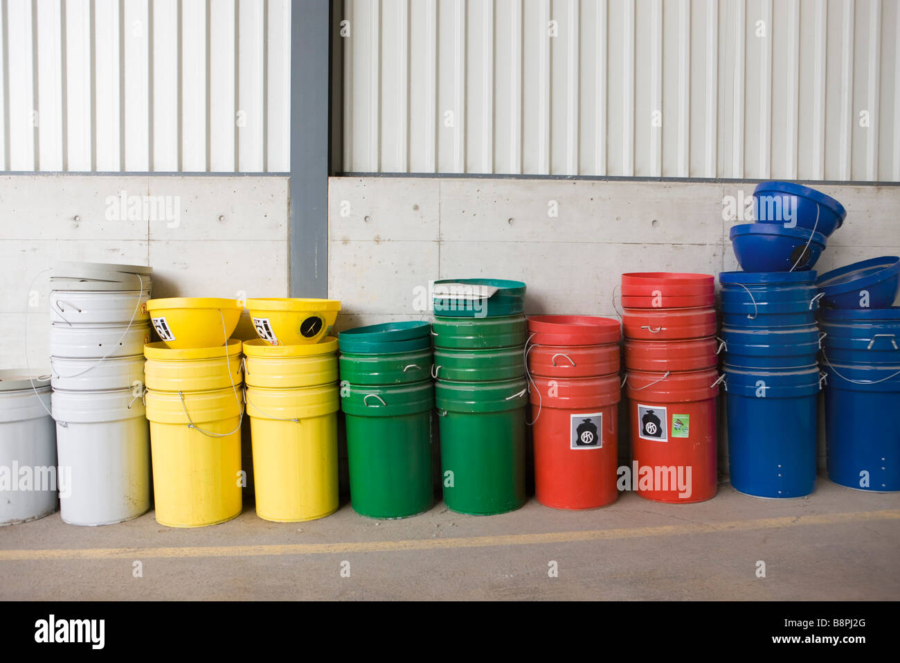 Multicolore di bidoni della spazzatura e cassonetti per il riciclaggio impilati lungo la parete Foto Stock