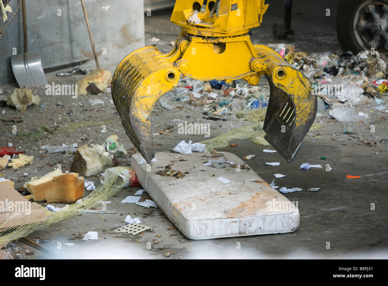 La benna mordente di prelevare il materasso in discarica di rifiuti Foto Stock