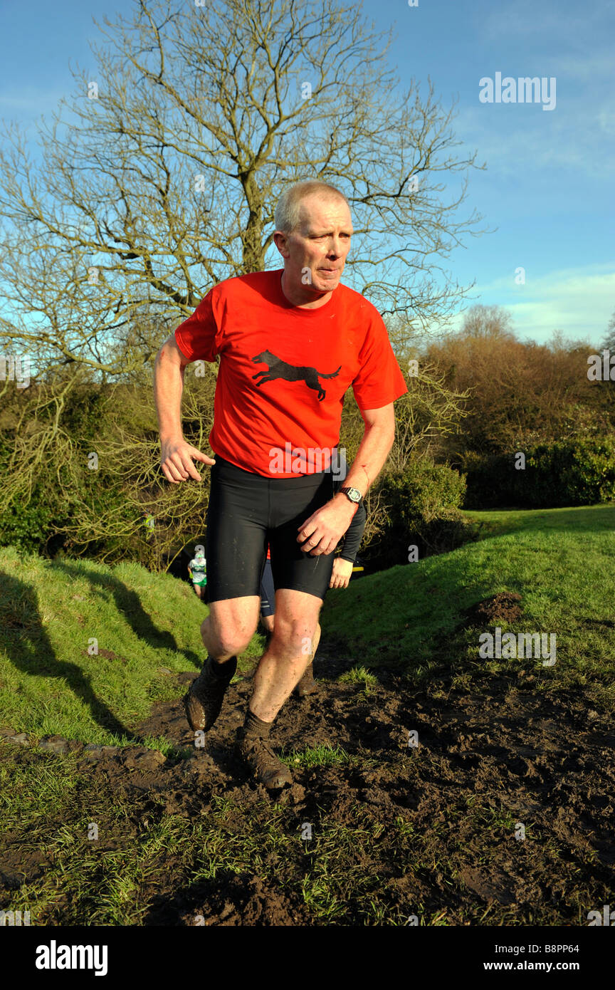 Uomo di mezza età in esecuzione fino tumulo erbosa nel cross country gara a framlingham suffolk Inghilterra 2009 Foto Stock