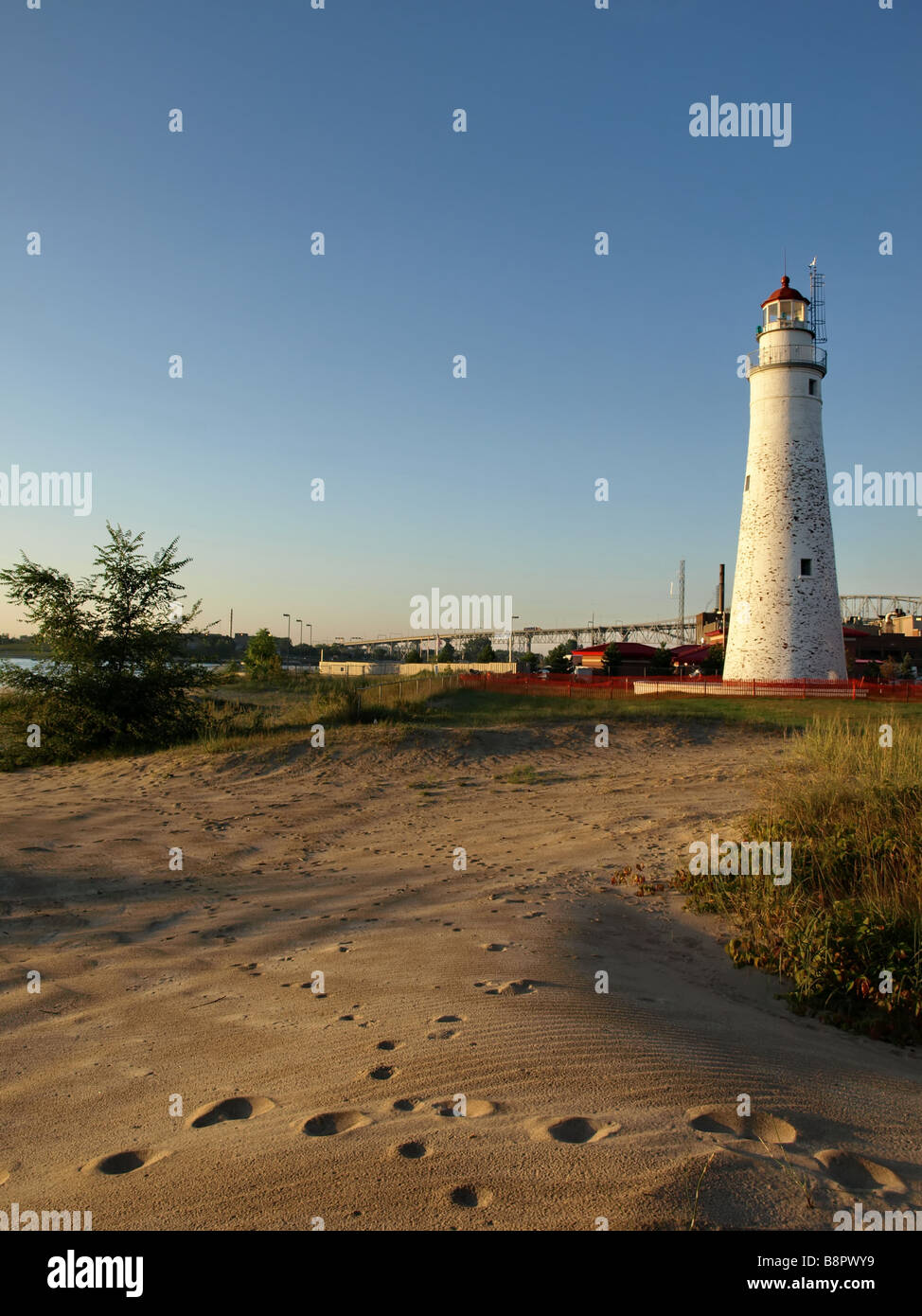 Fort Gratiot faro con acqua blu ponte in background e la spiaggia in primo piano vi sono le tracce degli animali nella sabbia. Foto Stock Fort Gratiot faro con acqua blu ponte in background e la spiaggia in primo piano vi sono le tracce degli animali nella sabbia. Foto Stock