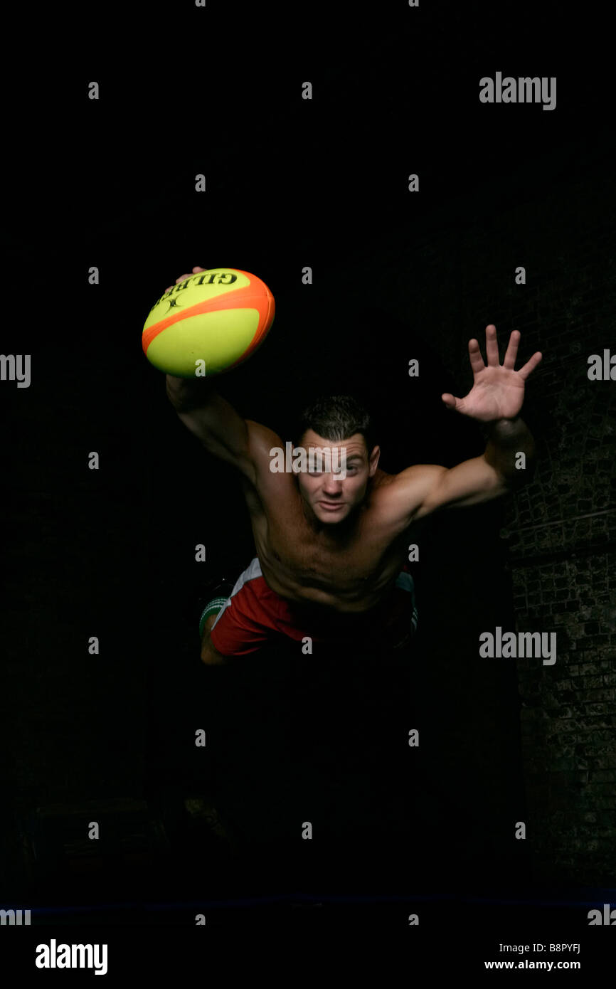 Il giocatore di rugby che si tuffa per la linea, esercitandosi dopo il lavoro dovunque può Sport nella città Foto Stock