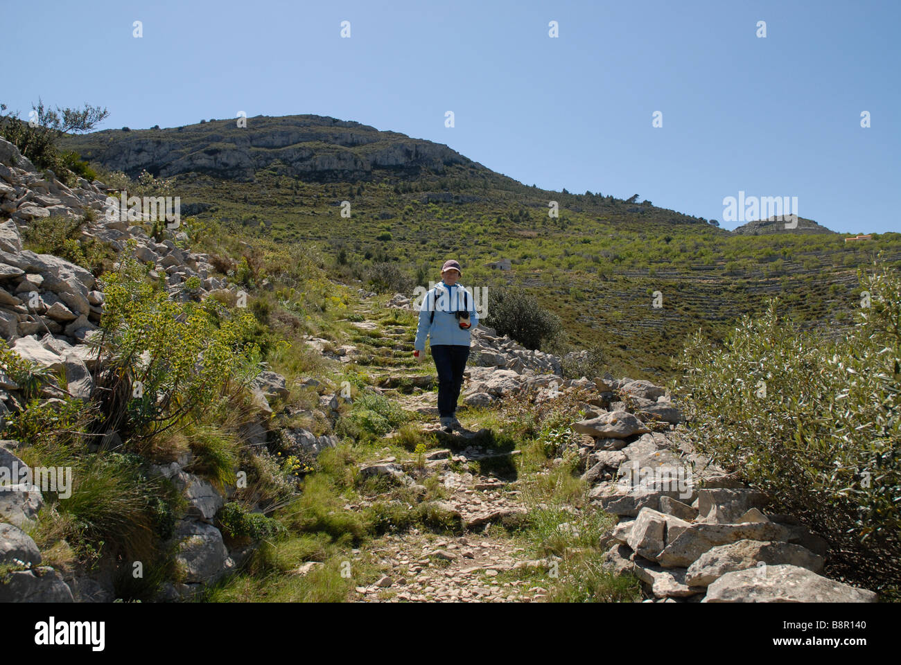 Donna escursionista con la fotocamera sul gradino sentiero mozarabico, Vall de Laguart, Benimaurell, Provincia di Alicante, Comunidad Valenciana, Spagna Foto Stock