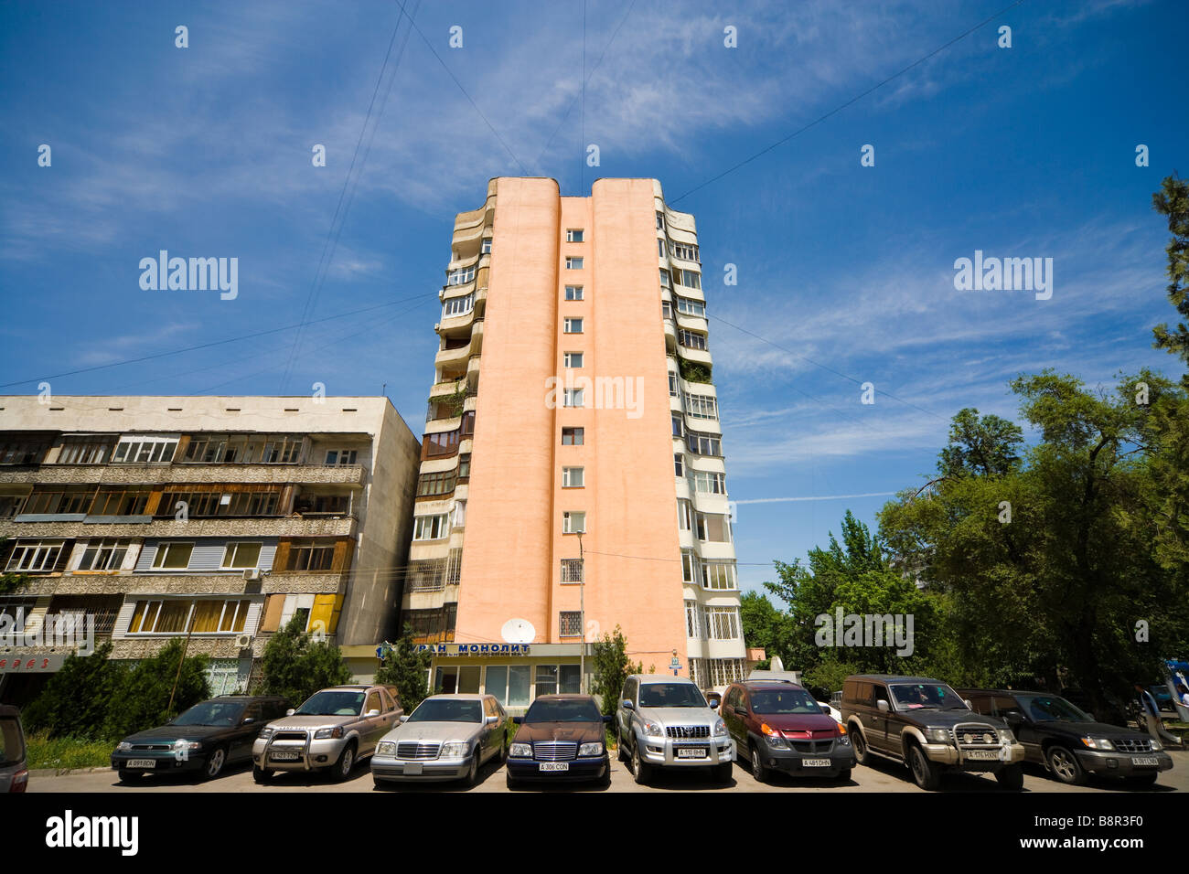 Una fila di automobili di lusso e suv, parcheggiato di fronte ad un edificio di appartamenti in Almaty, Kazakhstan. Foto Stock