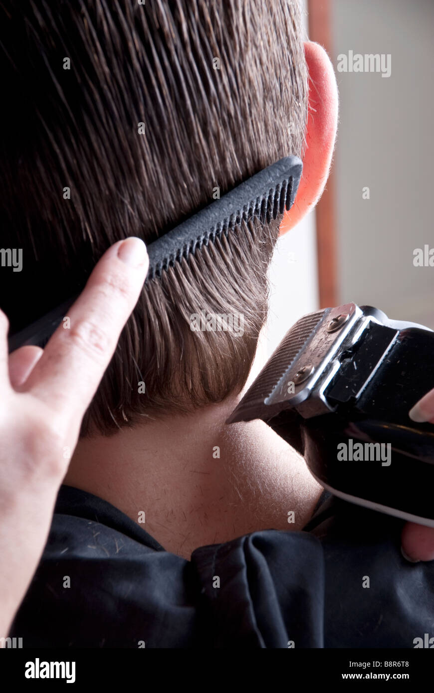 Un maschio avente i suoi capelli tagliati/tagliare in un barbiere Foto Stock