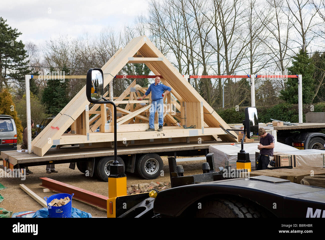 Operai in attesa di scarico rimanenti consegna attico capriate da una spedizione di blocchi di legno per tetti. Foto Stock