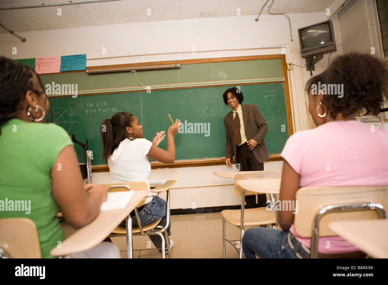Sorridente medio scuola studente interagisce con gli studenti rispondendo a una domanda in un'aula Foto Stock