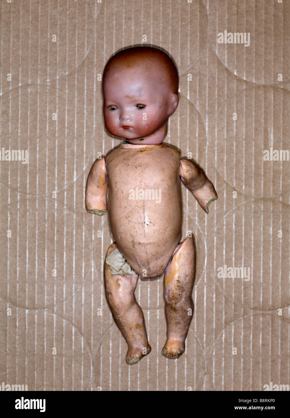 Studio shot del danneggiato bambola giocattolo in una scatola di cartone. Foto Stock