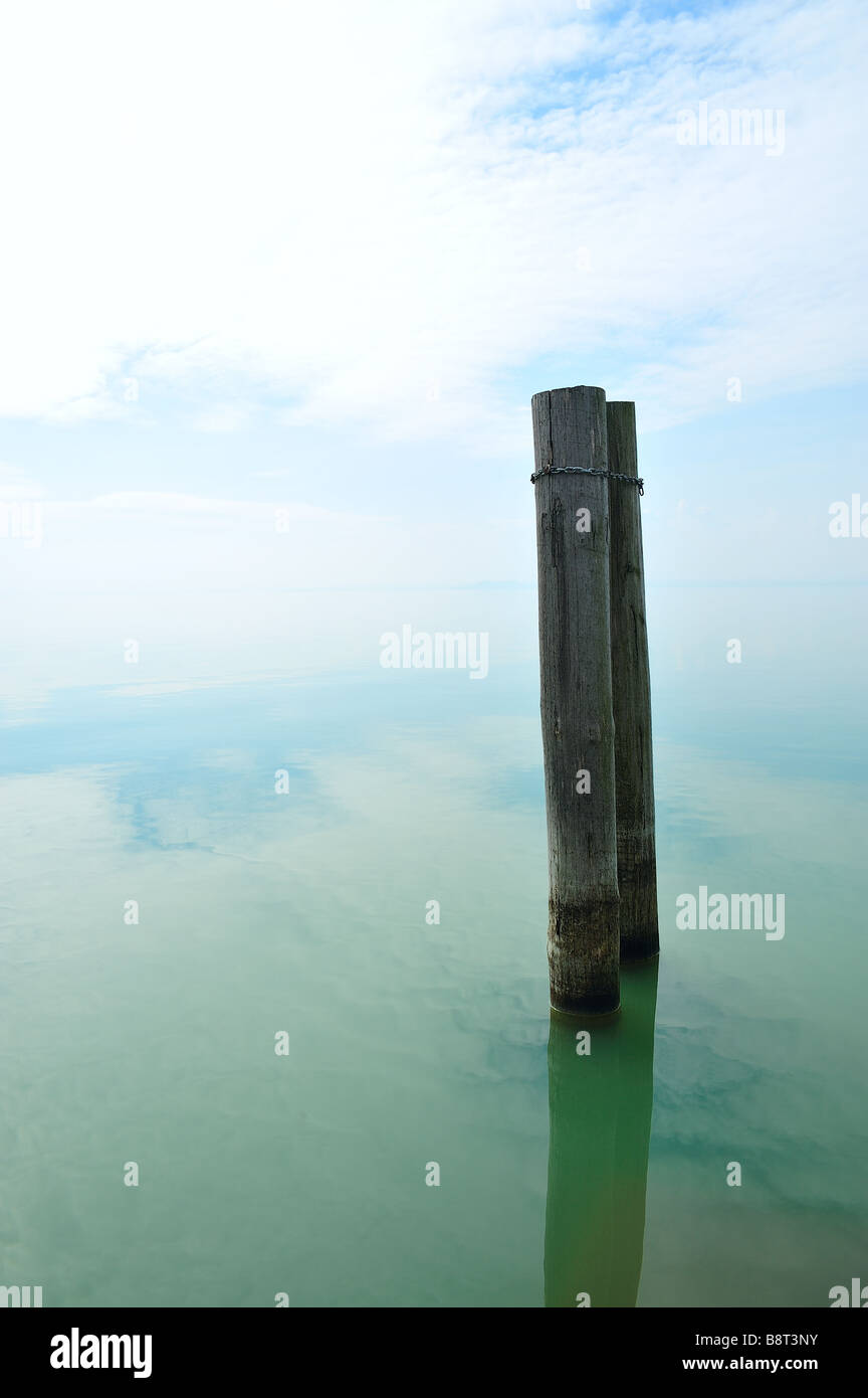 Due poli in una calma lakescape nuvoloso Foto Stock