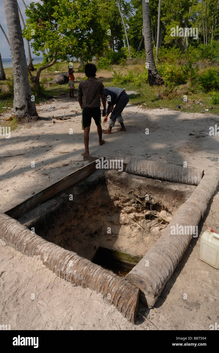 Acqua dolce pozzo scavato nella sabbia con i ragazzi la riproduzione in background Pulau Sibuan Semporna Sabah Borneo malese del sud-est asiatico Foto Stock