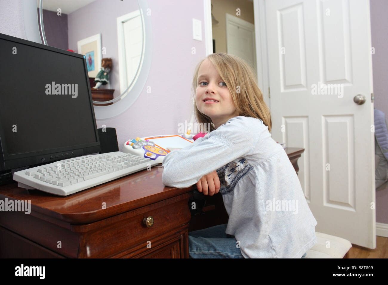 Giovane ragazza seduta al suo computer Foto Stock