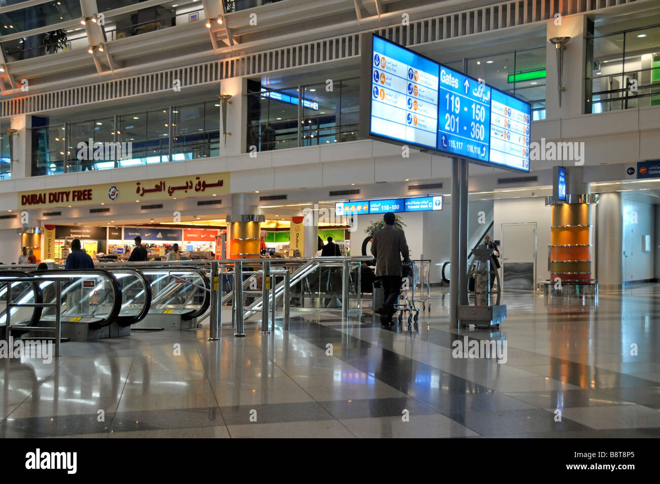 Aeroporto internazionale di Dubai passeggeri moderno interno saloni di partenza edificio scale mobili E duty free segno negozio Emirati Arabi Uniti UAE Medio Est Foto Stock