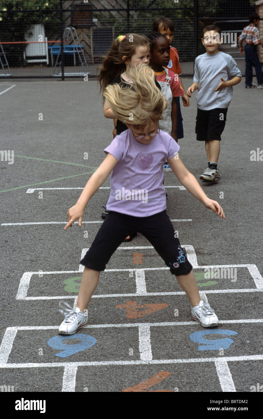 La scuola primaria ragazza giocando campana Foto Stock