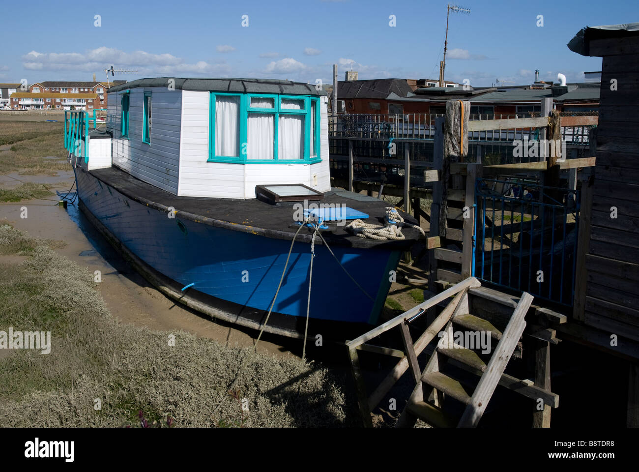 Un blu casa galleggiante in legno ormeggiate al fianco di un molo a Shoreham Beach, Sussex, Inghilterra Foto Stock