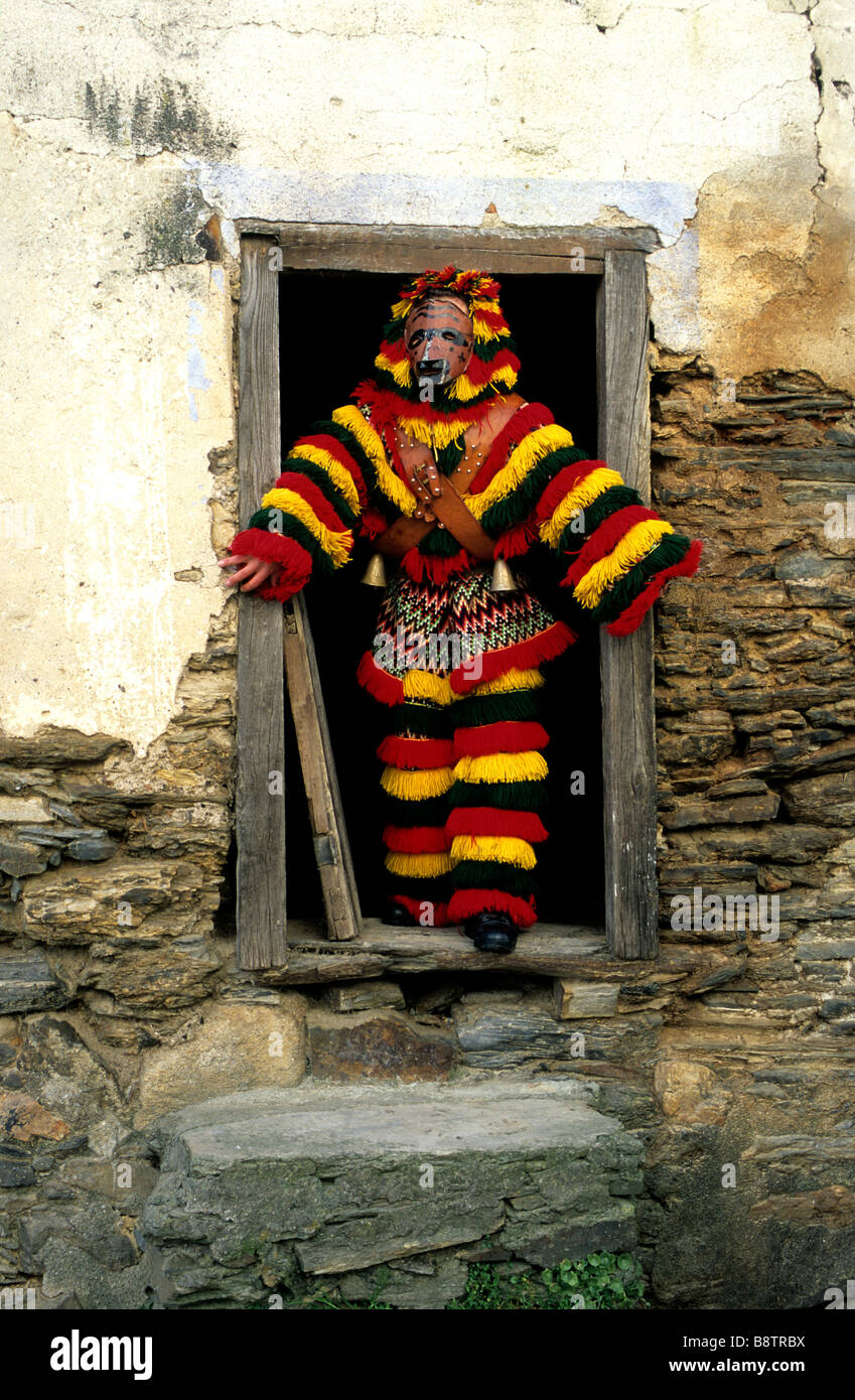 Un uomo vestito con una tradizione 'Caretos' costume incorniciato in una casa colonica porta durante il carnevale di celebrazioni in Podence, Portogallo Foto Stock