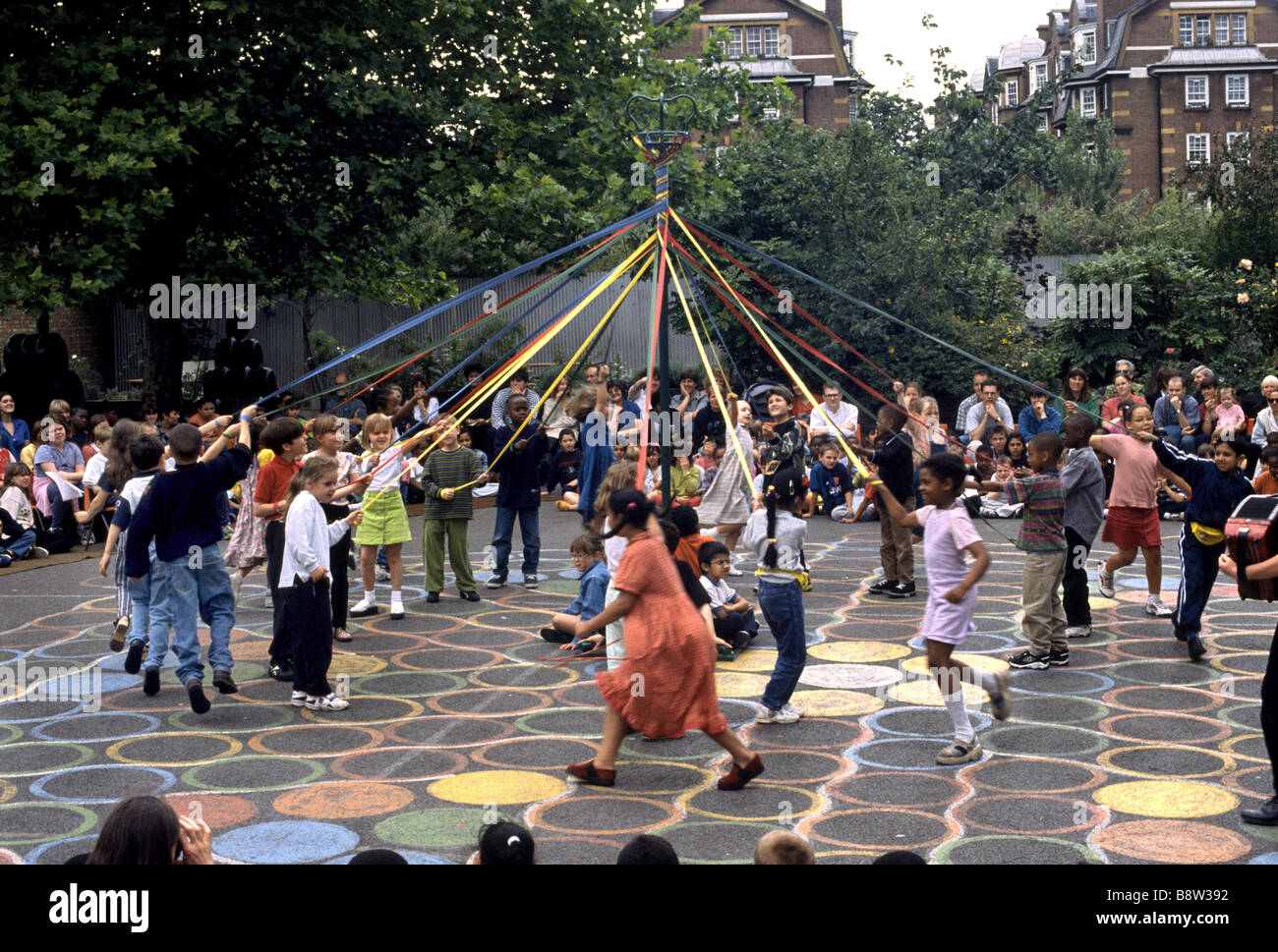 I bambini della scuola elementare celebrando giorno di maggio danza attorno al palo Foto Stock