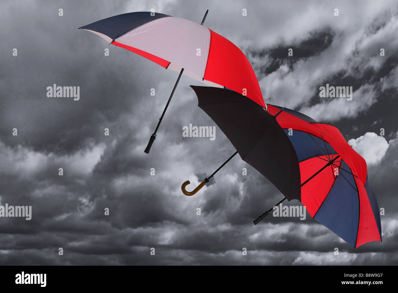 Tre ombrelloni di essere soffiata attraverso un buio tempestoso cielo molto nuvoloso Foto Stock