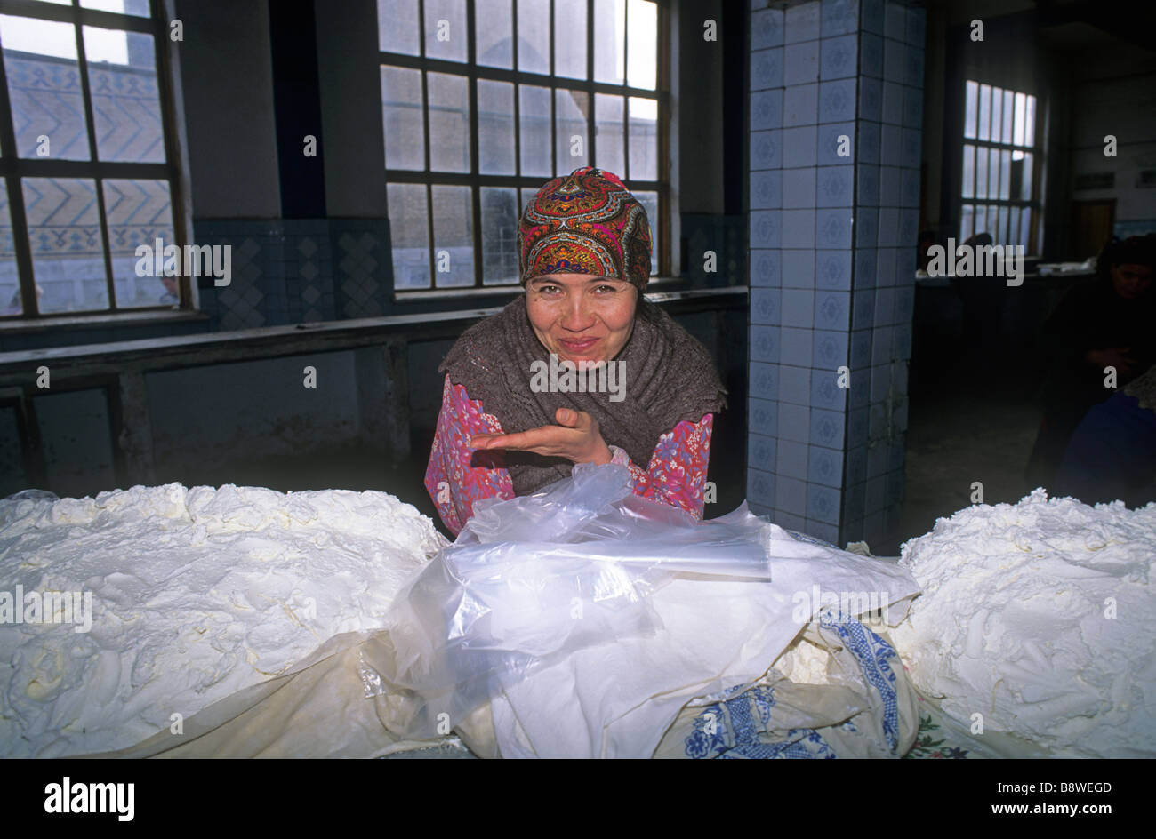 Donna stallholder vendita di formaggio cremoso Kolhoznaya bazaar coperto Samarcanda Uzbekistan Asia il bazar è premuto contro il Foto Stock