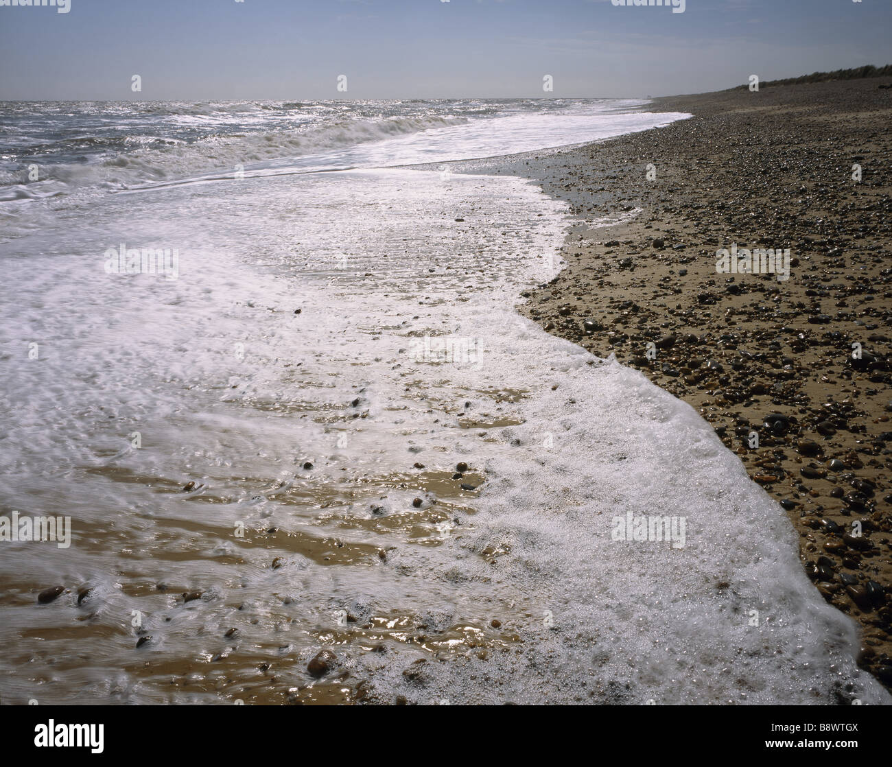 Surf sulla spiaggia di Minsmere a Dunwich Heath che mostra una spiaggia rocciosa con la rottura del mare su di esso Foto Stock