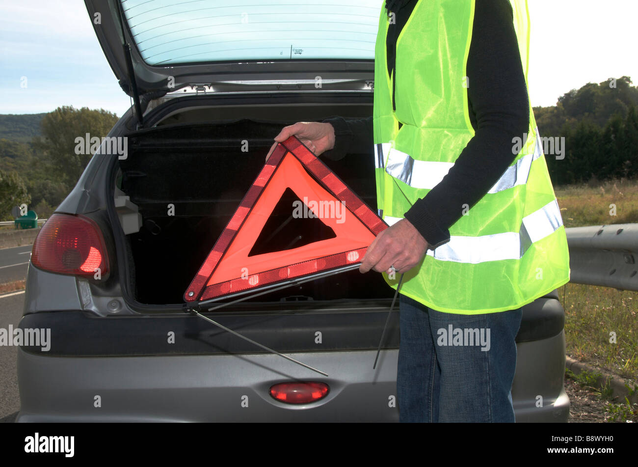 Donna getting triangolo al di fuori della sua ripartiti in auto Foto Stock