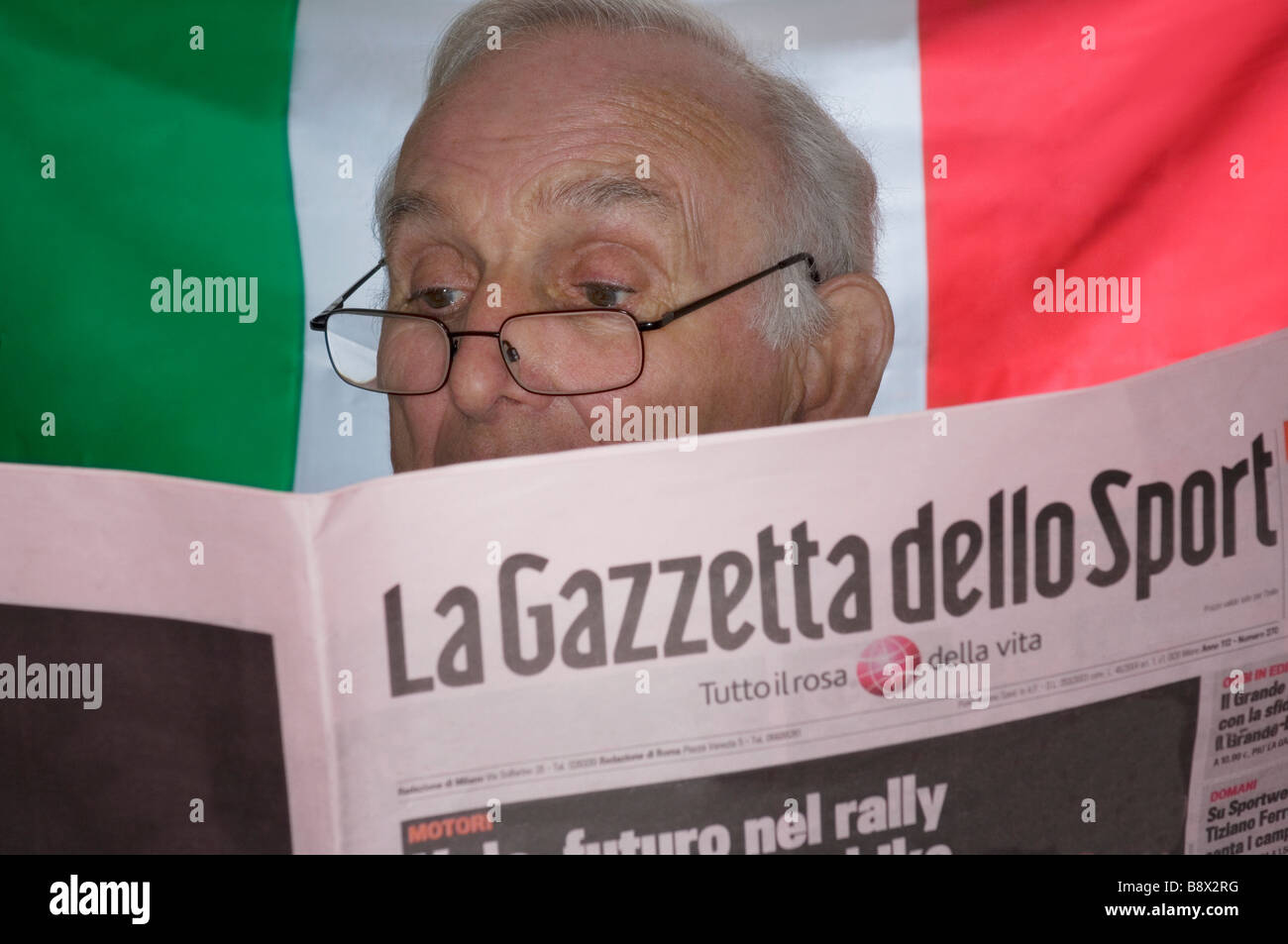 Italiano Senior uomo sport lettura carta - Nazionale Italiana di bandiera in background Foto Stock