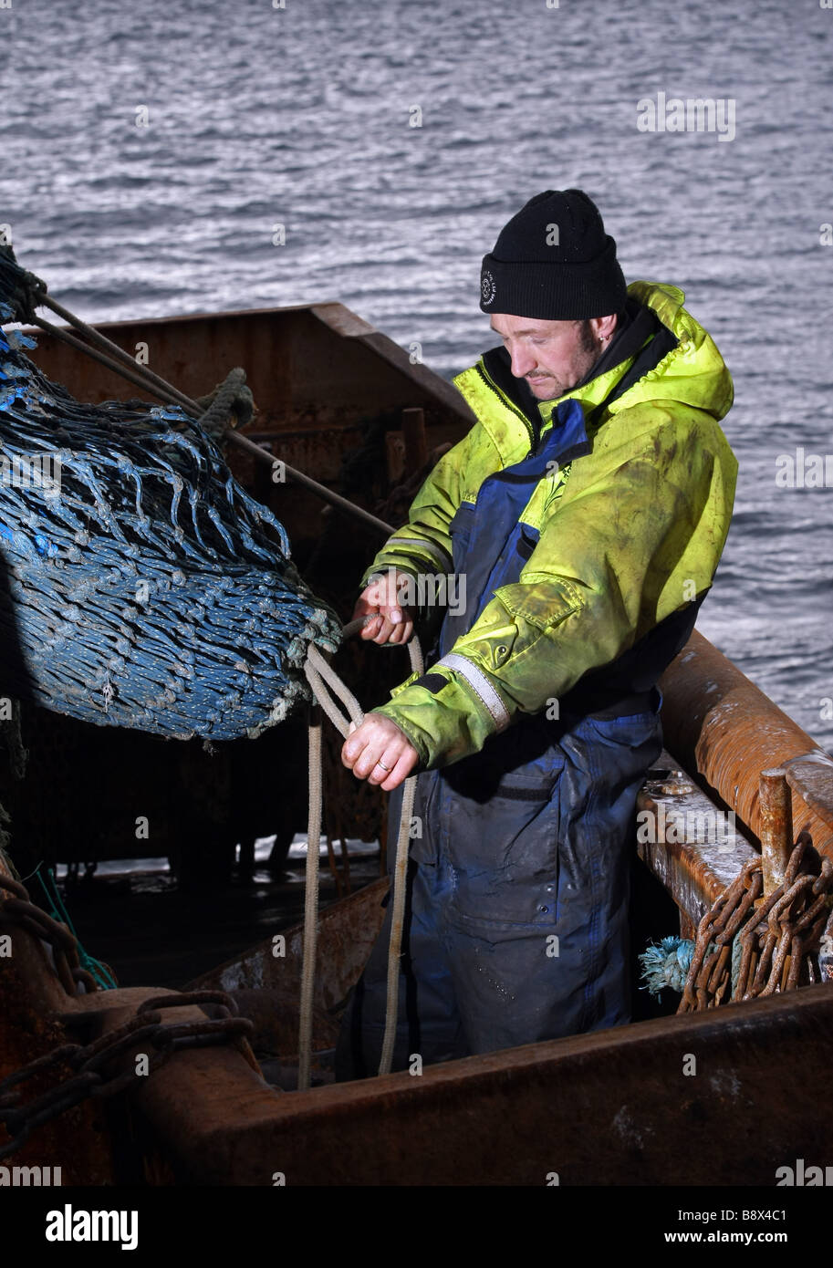 Mare del Nord pescatore in base a Peterhead, Scozia, lavorando su reti di una barca da pesca Foto Stock