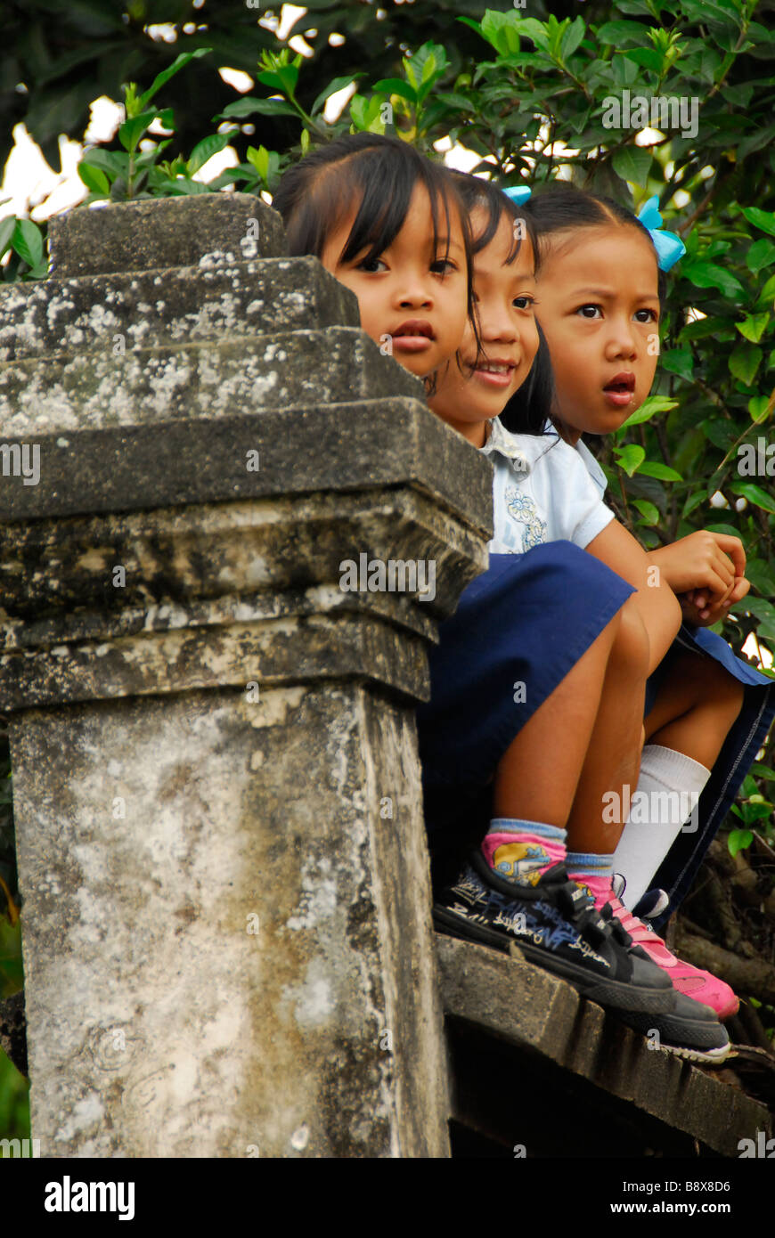 Scuola Balinese bambini e rilassante seduta sulla scuola di recinzione di cemento,Indonesia Foto Stock