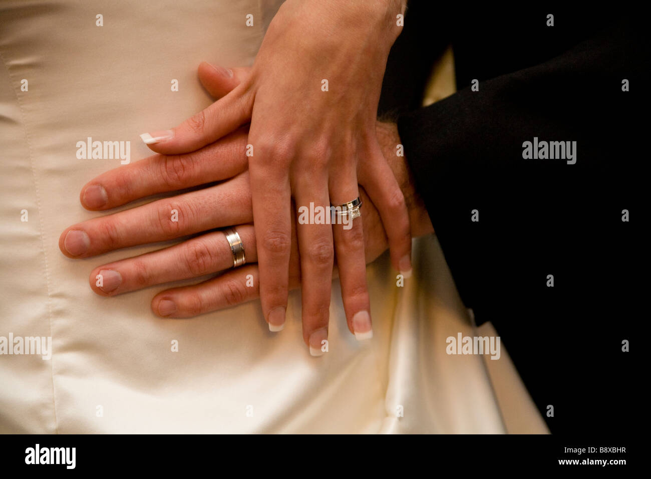 Un matrimonio giovane mostrare loro anelli contro le spose abito. Foto Stock