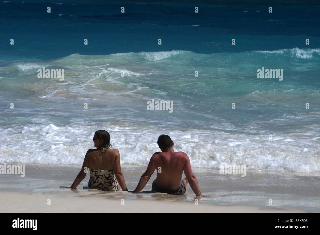 Matura in seduta il surf sulla spiaggia di gru Barbados Foto Stock