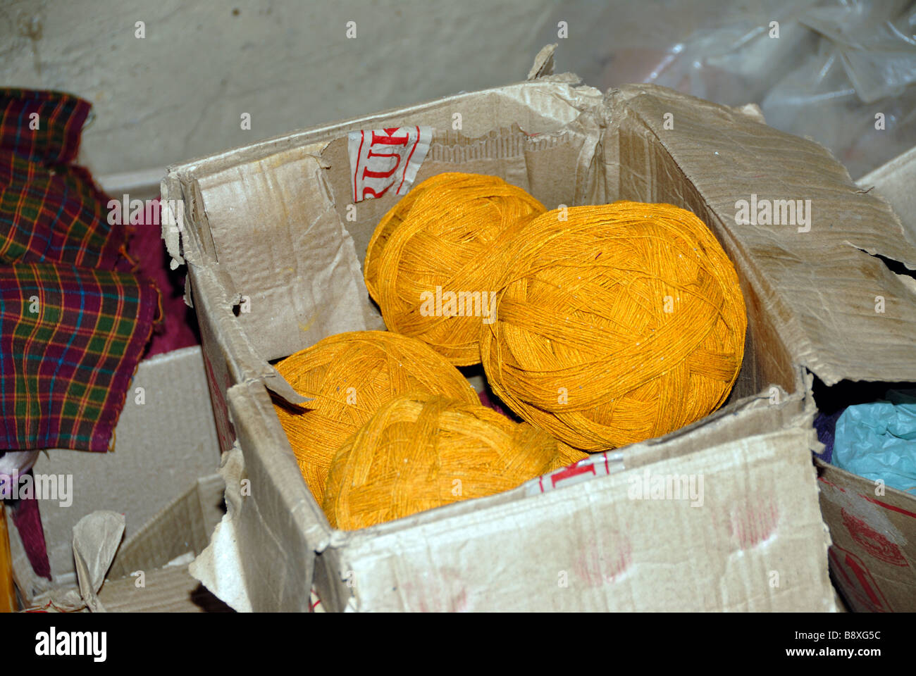 Palle di colore giallo brillante filo di seta in una vecchia scatola di cartone pronto per la tessitura Foto Stock