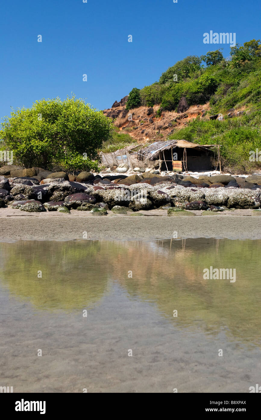 Capanna sulla spiaggia con lonely tree riflessa nell'acqua. Foto Stock