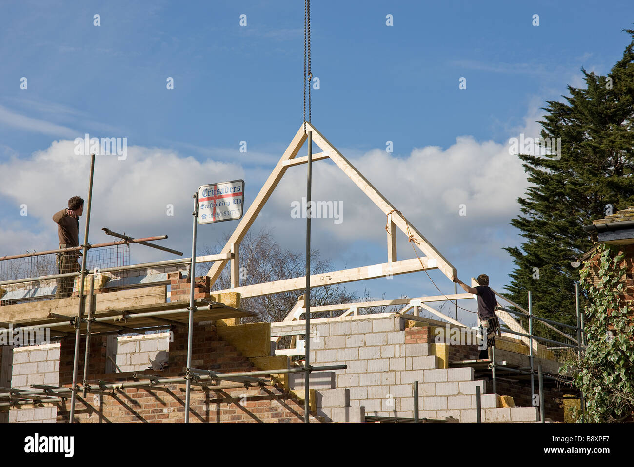 Il primo principale sul tetto soffitta architrave essendo abbassato nella posizione corretta pronto per iniziare a costruire il tetto per la nuova casa Foto Stock