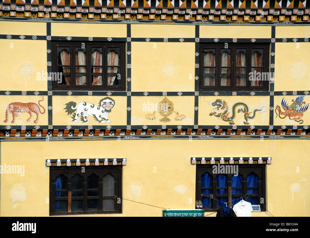 Un tradizionale edificio decorato con dipinti termina di fagiolo e bestie simbolico dipinto sul muro. Mongar, Bhutan Foto Stock