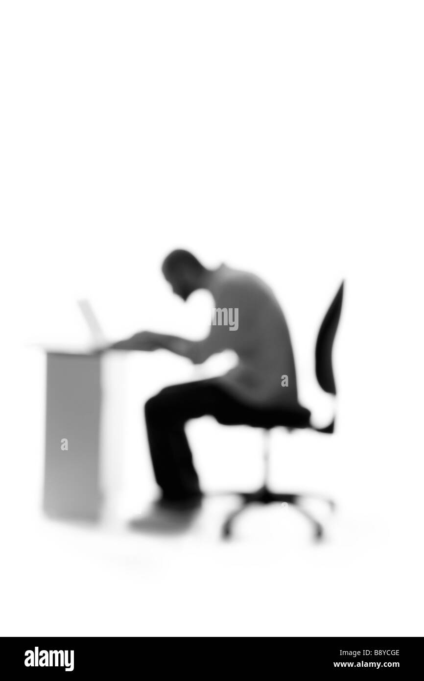 Silhouette di un uomo seduto da una scrivania. Foto Stock