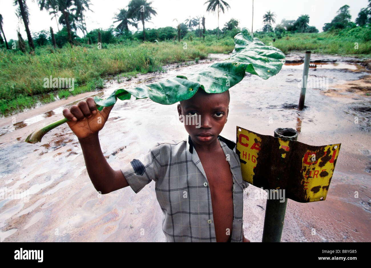 Nigeria: un ragazzo sorge oltre ad un segno di pericolo da un olio contaminato area in Ogoniland Foto Stock