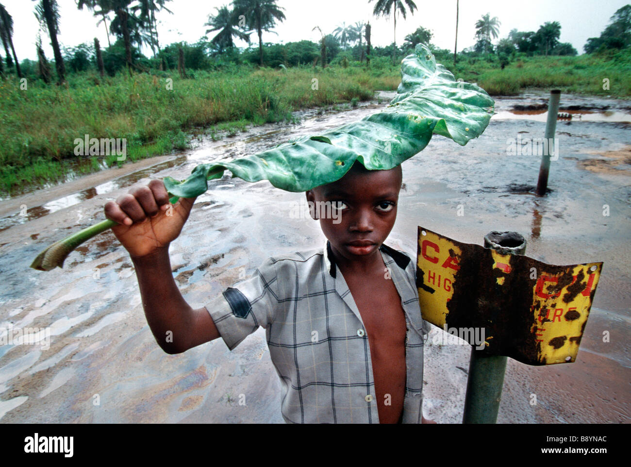 Nigeria: un ragazzo sorge oltre ad un segno di pericolo sul petrolio area contaminata in Ogoniland, Nigeria Foto Stock