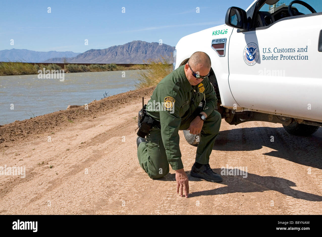 U S Pattuglia di Confine agent verifica per impronte in U S Messico confine lungo tutto il canale americano vicino Calexico California Foto Stock